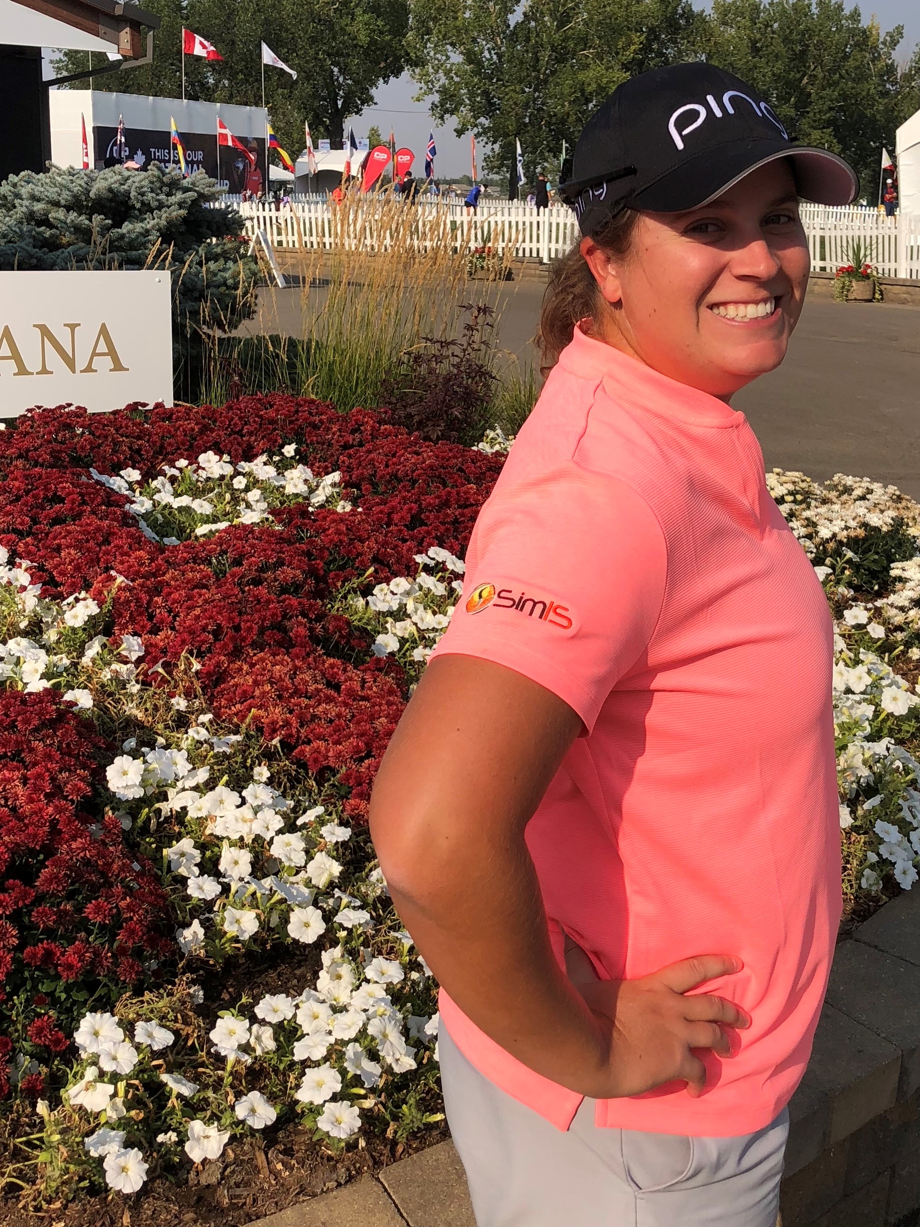 Lauren Coughlin smiling at a tournament, wearing a SimIS-branded golf shirt sleeve.