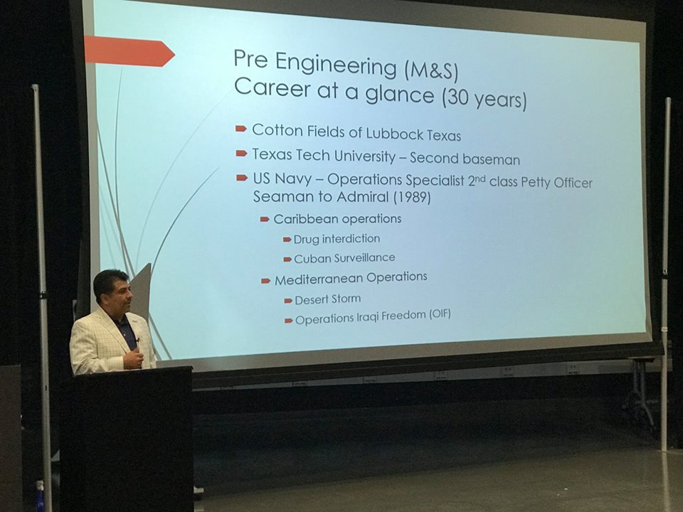 Dr. Johnny Garcia presenting a slide outlining his pre-engineering career timeline, from the cotton fields of Lubbock, Texas through his U.S. Navy service.